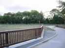 Western end of bridge with wooden railings.
Trees and footpath sign in background.