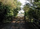 Wooden five-bar gate with trees each side.
River beyond gate.