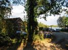 Taplow Lake Sailing Club.
Clubhouse seen through trees, with boats and parked cars.
Lake on the right.