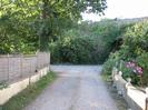 Track leading to junction with lane.
Low walls on each side.
Fence and trees on the left.
Railway bridge and embankment on the right.