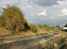 Road with railway embenkment on the left.
Bushes and grass on the embankment.
50mph speed limit signs each side of road.
Tall street-lights.