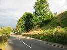 Looking east on Approach Road.
Grassy field and trees on left.
Railway embankment with trees on right.