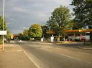 Looking east alon the A4 Bath Road.
Brick arch railway bridge in the distance.
Trees alongside road.
Shell filling station on the right.